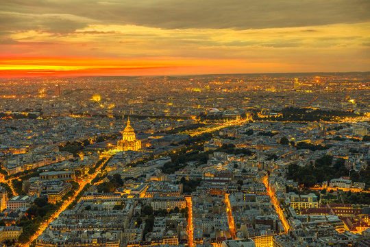 Paris urban skyline cityscape. Aerial view of national residence of the Invalids palace on orange sunset with night street light from panoramic terrace of Tour Montparnasse. European capital of France