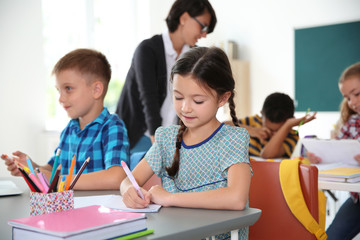 Adorable little children sitting at desks in classroom. Elementary school