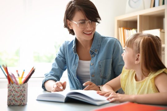 Female Teacher Helping Child With Assignment At School