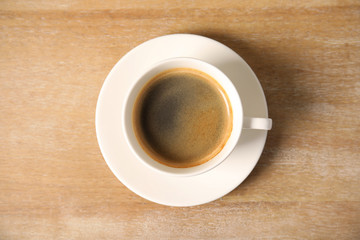 Cup of delicious hot coffee on wooden background, top view