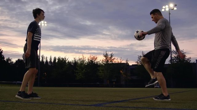American Father and Son Juggling Soccer Ball