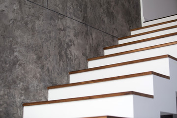 White and wooden stairs on black or grey stone wall in interior
