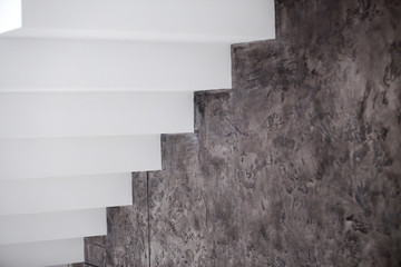 White and wooden stairs on black or grey stone wall in interior
