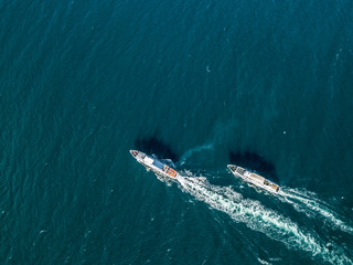 top view of two cruise ships in the open sea, one outrunning another