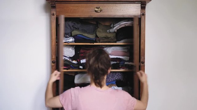 Young girl or woman open old retro vintage wooden wardrobe and search clothes, view from back, shot in 4K UHD