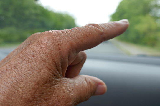Handzeichen. Handgesten.   Zeigefinger einer älteren Person, die im Auto sitzt und auf einen Gegenstand oder auf eine Situation zeigt 