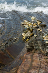 pebble stones on the sea beach, the rolling waves of the sea with foam