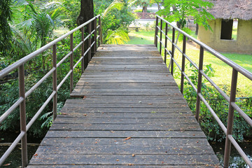 Naklejka na ściany i meble Old wooden bridge with metal rail in public park. 