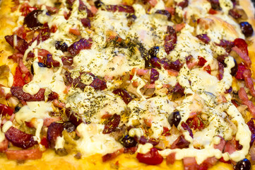 homemade pizza with peppers, plums, ham, sausage, cheese and spices, closeup