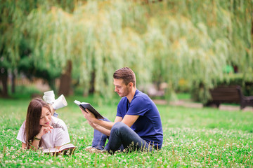 Relaxed young couple reading books while lying on grass