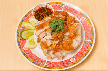 Fried chicken place on top the rice with cucumbers and sauce.