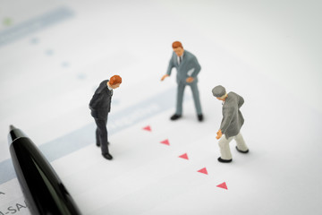 Financial crisis, decline or investment price drop concept, miniature professional businessmen standing and looking, review on red down arrows stock market data with shock and panic customer