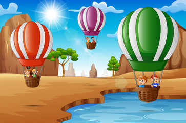 Naklejka premium Cartoon happy kids riding hot air balloon in the desert 