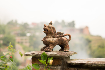 Guarding lion stone figure and old oil lamp in front of a hill landscape in Bandipur, Nepal.