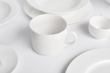 selective focus of various plates, bowl and cup on white table