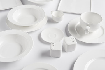 close up view of different plates, cup, bowl, saltcellar and pepper caster on white table