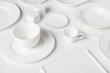 close up view of different plates, bowl, cup, saltcellar and pepper caster on white table