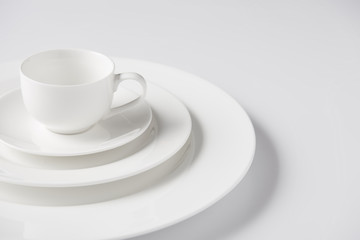 close up image of cup on stack of different plates on white table