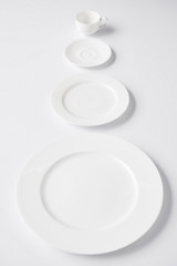 selective focus of arranged various plates and cup on white table
