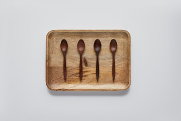 top view of wooden tray with wooden spoons on white table, minimalistic concept