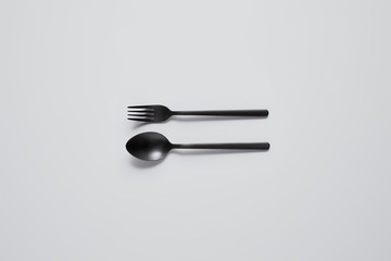 top view of black spoon and fork on white table, minimalistic concept
