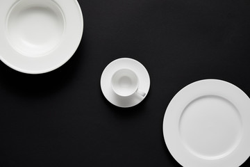 top view of arranged different plates and cup on black table