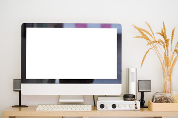 Modern desktop pc white blank screen and little loudspeaker on wooden work table.