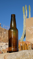 Empty glass bottle on a desert like background with clear blue sky