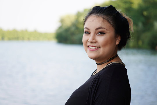 happy young asian woman standing at lakeside