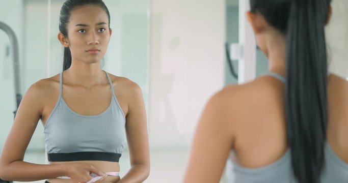 Woman at the gym struggling with her weight in front of the mirror