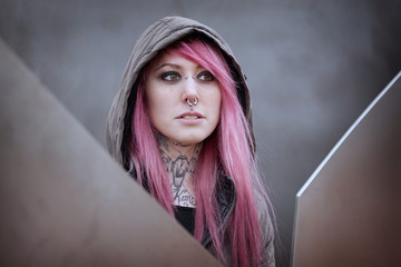 young alternative woman with pink hair piercings and tattoos gazing into distance                              