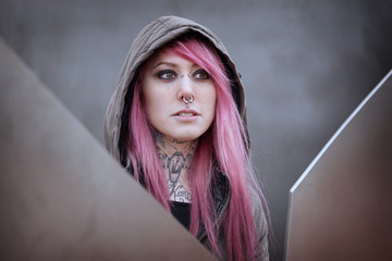 young alternative woman with pink hair piercings and tattoos gazing into distance                  ...