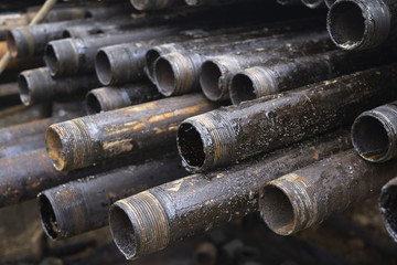 Oil Drill pipe. Rusty drill pipes were drilled in the well section. Downhole drilling rig. Laying the pipe on the deck. View of the shell of drill pipes laid in courtyard of the oil and gas warehouse.