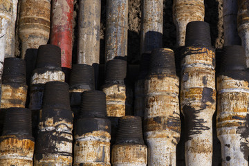 Fototapeta premium Oil Drill pipe. Rusty drill pipes were drilled in the well section. Downhole drilling rig. Laying the pipe on the deck. View of the shell of drill pipes laid in courtyard of the oil and gas warehouse.