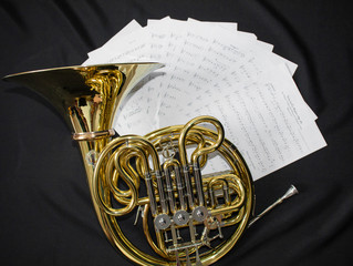 Musical instrument French horn lies on a black background with notes