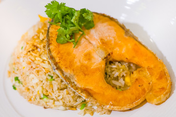 fried sliced salmon with fried rice.man hands use fork and spoon for fusion food.sliced salmon with...