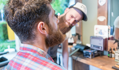Close-up of the head of a redhead bearded young man ready for a trendy haircut under the guidance of a dedicated hairstylist