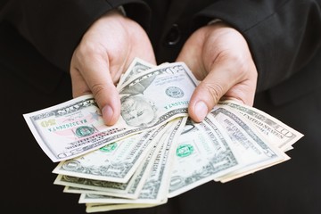 Business man in formal suit close up hand hold money spread of cash giving money.