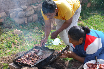 Native american people cooking meat in the countryside. 