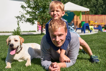 Obraz premium Happy family on the grass with a wonderful labrador