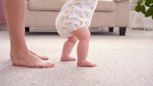 Mother teaching her baby first steps at home