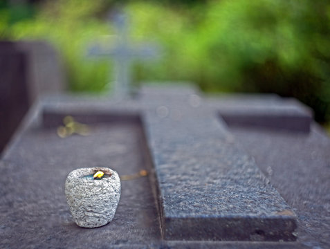 Granite Tombstone In The Shape Of A Cross With A Candle And Blurred Background