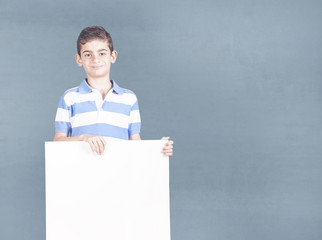 Cute little boy holding a blank white sign with copy space