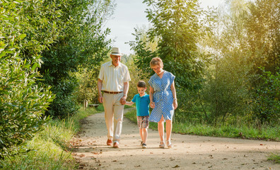 Front view of grandparents and grandchild walking on a nature path