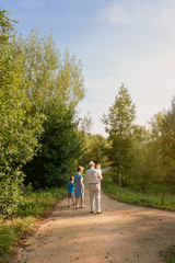 Back view of grandparents and grandchildren walking on a nature path