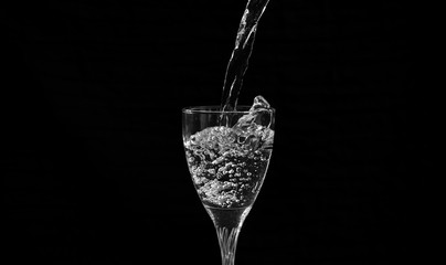water falling in a transparent wine glass creating splash and bubbles