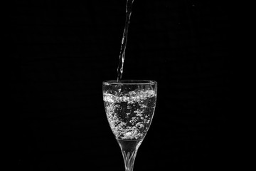water falling in a transparent wine glass creating splash and bubbles