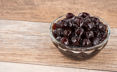 Tapioca Pearl , Bubble topping for tea or other beverage, in a cup, place on wooden table. Copy space