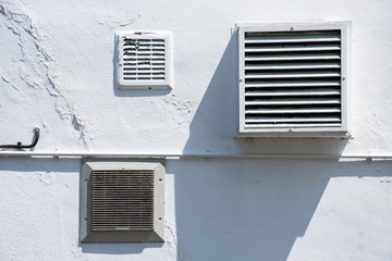 Ventilation grills on a white wall in bright sunlight