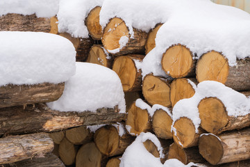 Firewood covered with snow stacked up in a pile for kindle